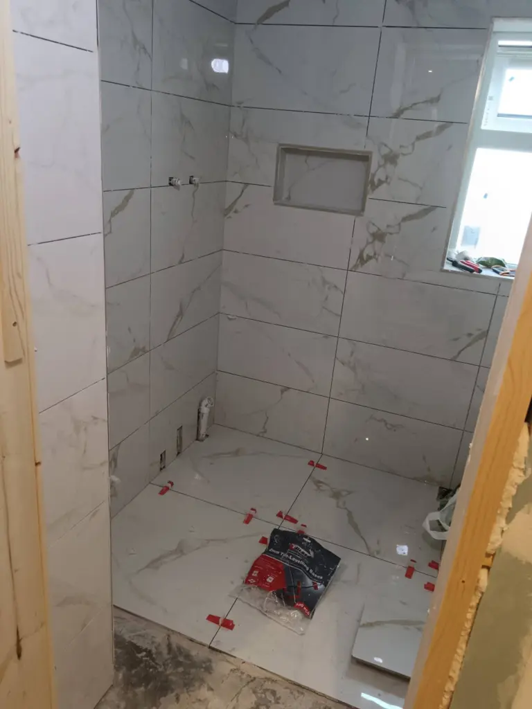Walk-in shower area with marble-effect walls and floor